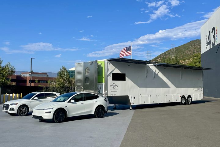 A 53-foot ECOLUXE solar trailer parked on a studio lot with electric cars beside it